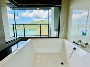een groot wit bad met een groot raam bij 水秀一方Sun Moon Lakeside Boutique Hotel in Yuchi