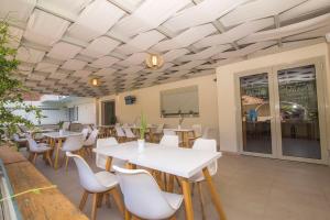 a dining room with tables and white chairs at AκrotiriResort in Vasiliki