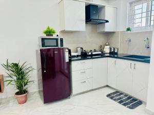 a kitchen with a purple refrigerator and a microwave at Olive Serviced Apartments BTM Layout in Bangalore