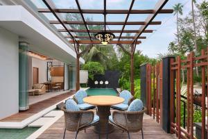 un patio con mesa, sillas y piscina en Four Points by Sheraton Bintan, Lagoi Bay, en Lagoi