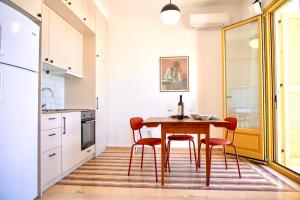 Port view apartment Aegina في ايجينا تاون: مطبخ مع طاولة خشبية وكراسي حمراء