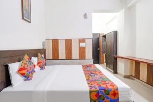 a bedroom with a large white bed with colorful pillows at FabHotel Prashant Palace in Agra