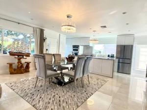 cocina y comedor con mesa de cristal y sillas en Luxury White Beach House en Redondo Beach