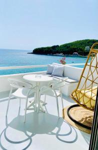 una mesa blanca y sillas en un balcón con vistas al océano en Geo & Art Boutique Hotel Himara, en Himare