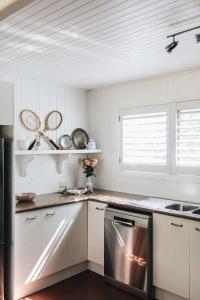 een keuken met witte kasten en een roestvrijstalen vaatwasser bij Coromandel Cottage, Berrima in Berrima