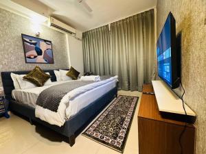una camera con letto e TV a schermo piatto di Celestial Chic Suite With Swimming Pool a Lucknow