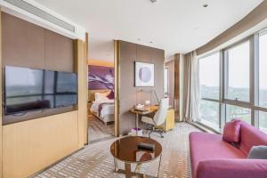 鄭州市にあるNovotel Zhengzhou Airportのソファとテレビがあるホテルの部屋