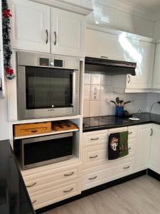 Una cocina con gabinetes blancos y un microondas. en Blouberg Beach Villa, en Ciudad del Cabo