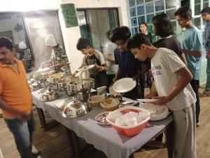 un grupo de personas de pie alrededor de una mesa preparando comida en Singanama RESORT, en Pachmarhī