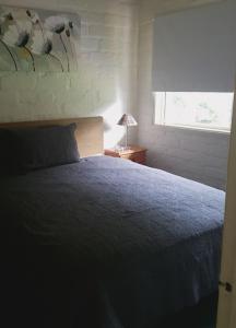 a bedroom with a bed with a blue blanket and a window at Quiet Country Retreat in Forster