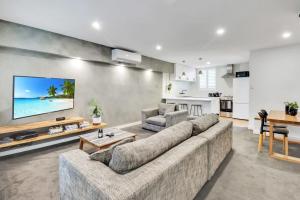 a living room with a large couch and a kitchen at Sherbourne Retreat in Newtown in Geelong