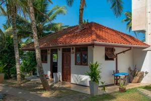 une petite maison blanche avec un toit rouge dans l'établissement Swiss Residenz, à Weligama