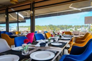 une salle à manger avec des tables et des chaises ainsi qu'une grande fenêtre dans l'établissement First Suites Hôtel, à Rabat