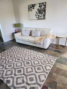 uma sala de estar com um sofá branco e um tapete em Beautiful and cozy home em Glenunga