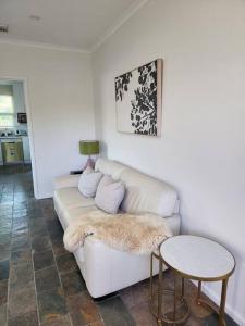 a living room with a white couch and a table at Beautiful and cozy home in Glenunga