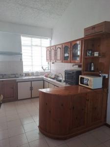 a kitchen with wooden cabinets and a microwave on a counter at Le Residence Blue Bay in Blue Bay