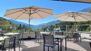 Un patio con mesas, sillas y sombrillas. en Gasthof Majestic, en Bresanona