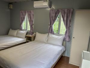 2 Betten in einem Zimmer mit 2 Fenstern in der Unterkunft 鉄木彩虹小屋 in Yü-lan