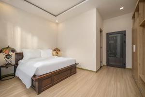 a bedroom with a large white bed and a door at Tashi Apartment in Da Nang