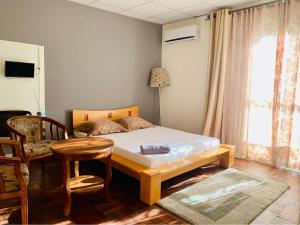 a bedroom with a bed and a table and a chair at Victoria Hôtel in Fianarantsoa