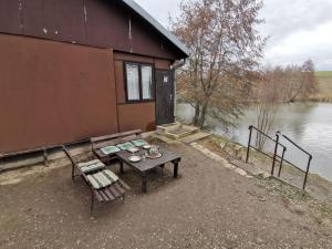 a table and chairs next to a building next to a lake at Rybářský bungalov in Olbramkostel