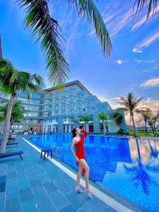 Duy Tân Quảng Bình Hotel & Resort في دونغ هوي: امرأة بلبس احمر تقف بجانب مسبح
