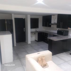 a kitchen with black cabinets and a white couch at BOSS Accomodation 6 in Durban