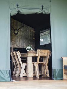a wooden table and chairs in front of a door at Sandringham Safari Tent Lodge in South Creake