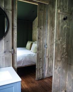a bedroom with a bed in a room with wooden walls at Sandringham Safari Tent Lodge in South Creake