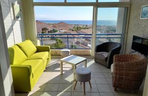 a living room with a yellow couch and a large window at PLEINE VUE MER PISCINE duplex parking privé fibre wifi plage 6 minutes a pied st pierre la mer in Fleury