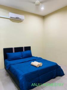 Un dormitorio con una cama azul con una toalla. en ANJU HOMESTAY BEAUFORT en Beaufort