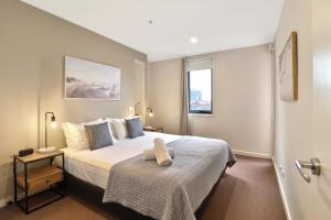 a bedroom with a bed with a white bedspread and a window at Terminus Apartment I Steps from Geelongs Buzz in Geelong
