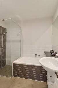 a bathroom with a tub and a sink and a shower at Terminus Apartment I Steps from Geelongs Buzz in Geelong