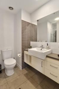 a white bathroom with a toilet and a sink at Terminus Apartment I Steps from Geelongs Buzz in Geelong