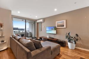 a living room with a couch and a large window at Terminus Apartment I Steps from Geelongs Buzz in Geelong