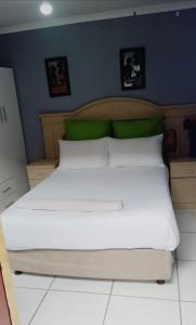 a bed with white sheets and green pillows in a bedroom at Nasrec Guesthouse in Johannesburg