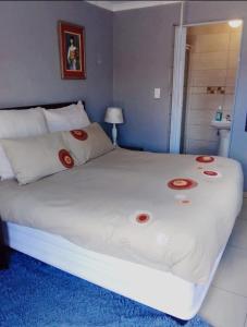 Nasrec Guesthouse في جوهانسبرغ: غرفة نوم بسرير ابيض كبير عليها ديكورات حمراء
