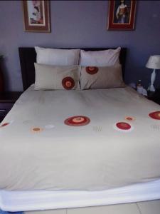 Nasrec Guesthouse في جوهانسبرغ: سرير أبيض كبير ومخدات حمراء عليه