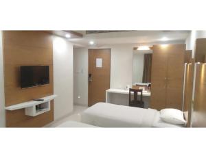 a bedroom with a bed and a tv and a desk at Hotel Maurya International, Chennai in Chennai