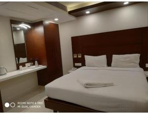 a bedroom with a large white bed and a mirror at Hotel Maurya International, Chennai in Chennai