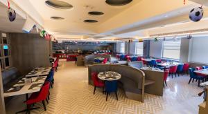 un comedor con mesas y sillas y un restaurante en Ramada by Wyndham Lucknow Hotel and Convention Center, en Lucknow