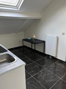 uma cozinha com piso em azulejo preto e uma mesa em argonne gare du midi 29 em Bruxelas