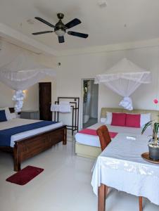 a bedroom with two beds and a ceiling fan at Sea Bay Inn Tangalle in Tangalle