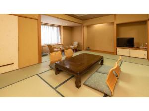 ein Wohnzimmer mit einem Holztisch und Stühlen in der Unterkunft Hotel Kunitomi Annex - Vacation STAY 12075v in Itoigawa