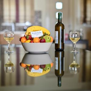 a bottle of wine and a bowl of fruit next to two wine glasses at Sand Lily Residence in Plakias
