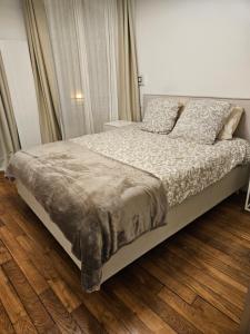 een bed in een slaapkamer met een houten vloer bij Somptueux appartement proche stade de france in Enghien-les-Bains