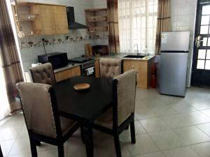 eine Küche mit einem schwarzen Tisch und Stühlen sowie einem Kühlschrank in der Unterkunft FABRISSA HOMES in Arusha