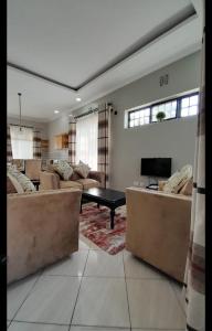 ein großes Wohnzimmer mit Sofas und einem TV in der Unterkunft FABRISSA HOMES in Arusha