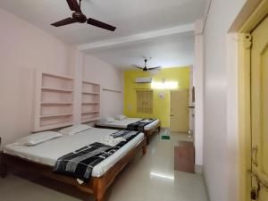 1 dormitorio con 2 camas y ventilador de techo en Shivangi Eco, en Puri