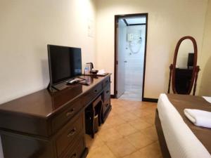 um quarto com uma cómoda e uma televisão em Cabana Republic em Puerto Princesa